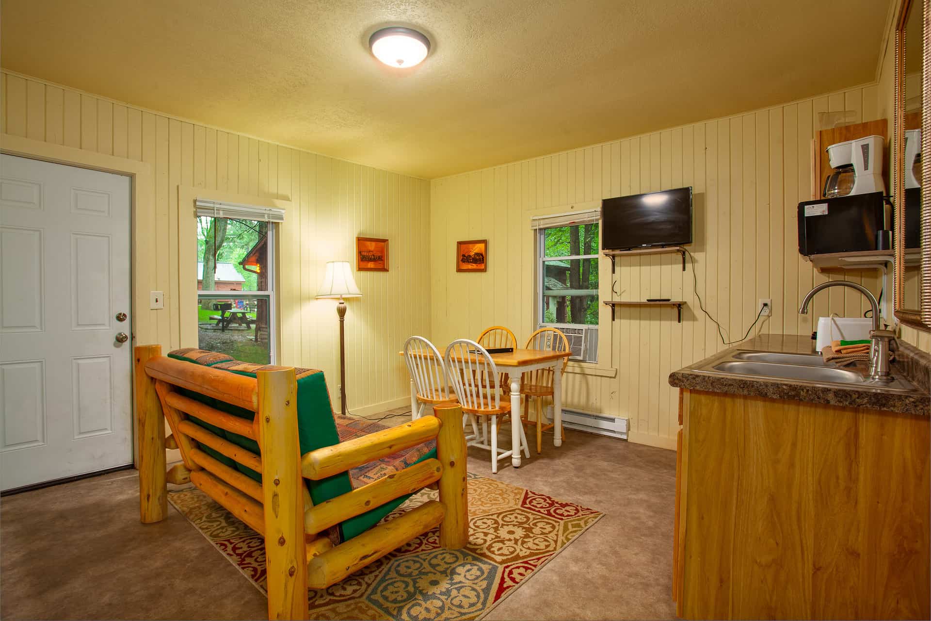 An open living area with rustic log furniture, a compact kitchen, and a dining nook.