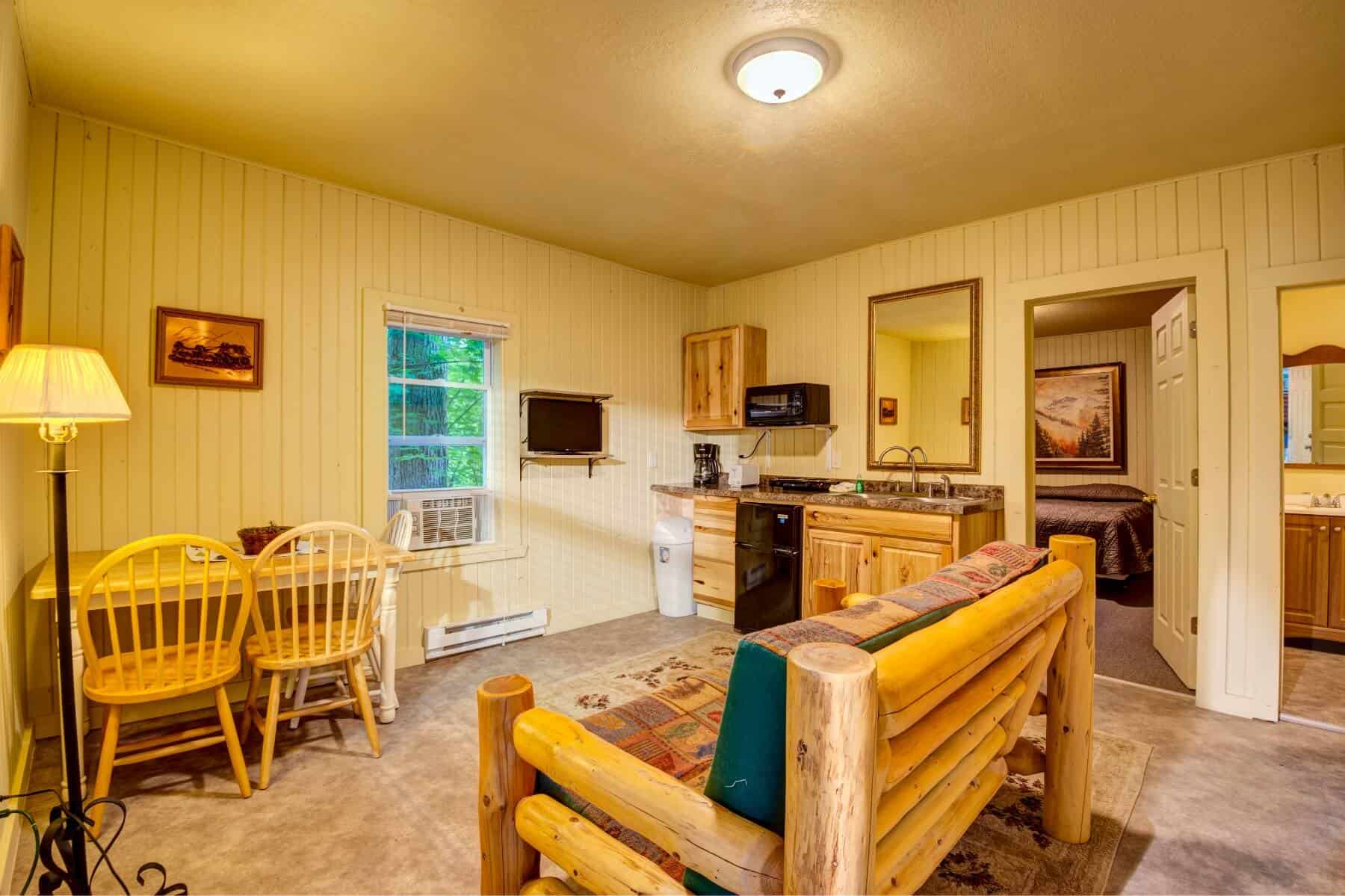An open living area with rustic log furniture, a compact kitchen, and a dining nook.