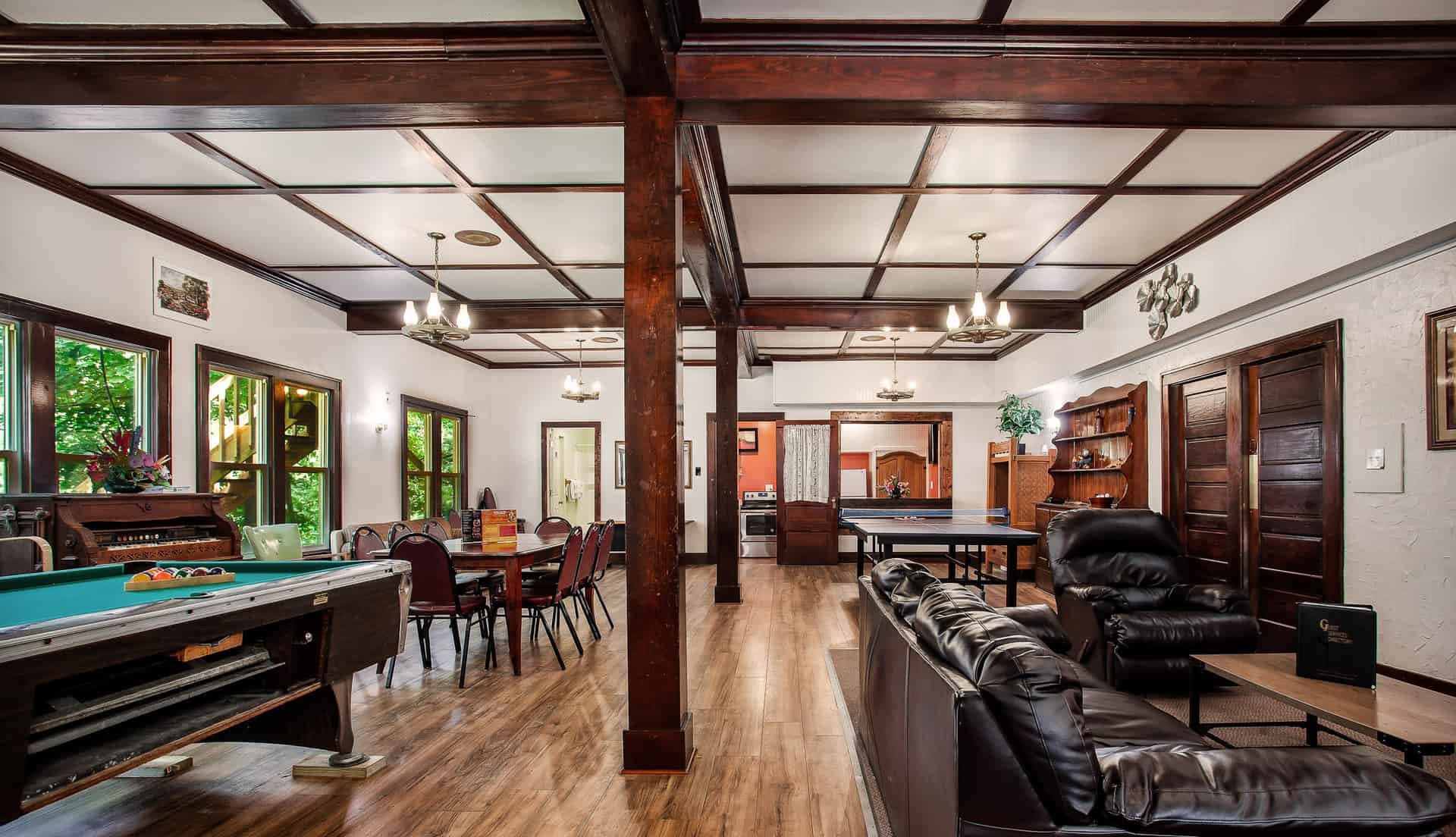 Spacious living area featuring a pool table, dining setup, and comfortable seating with wooden beams.