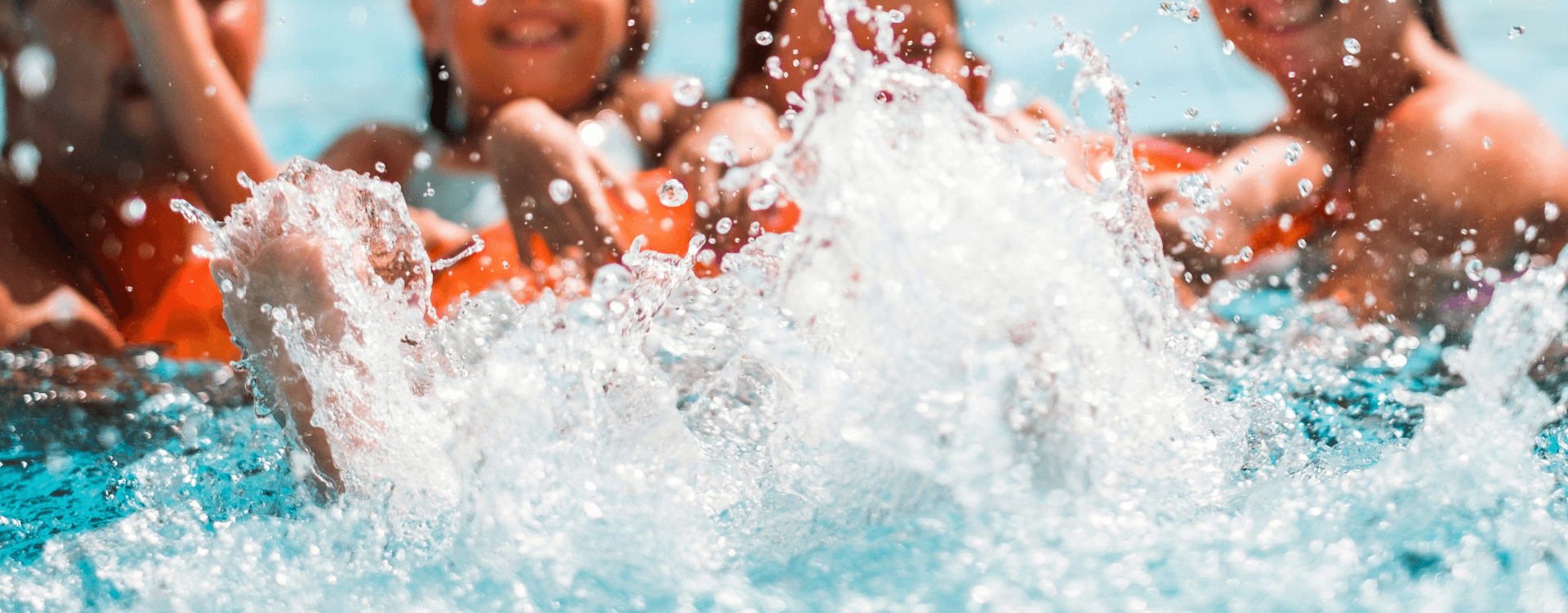 A group of kids splashes playfully in a swimming pool.