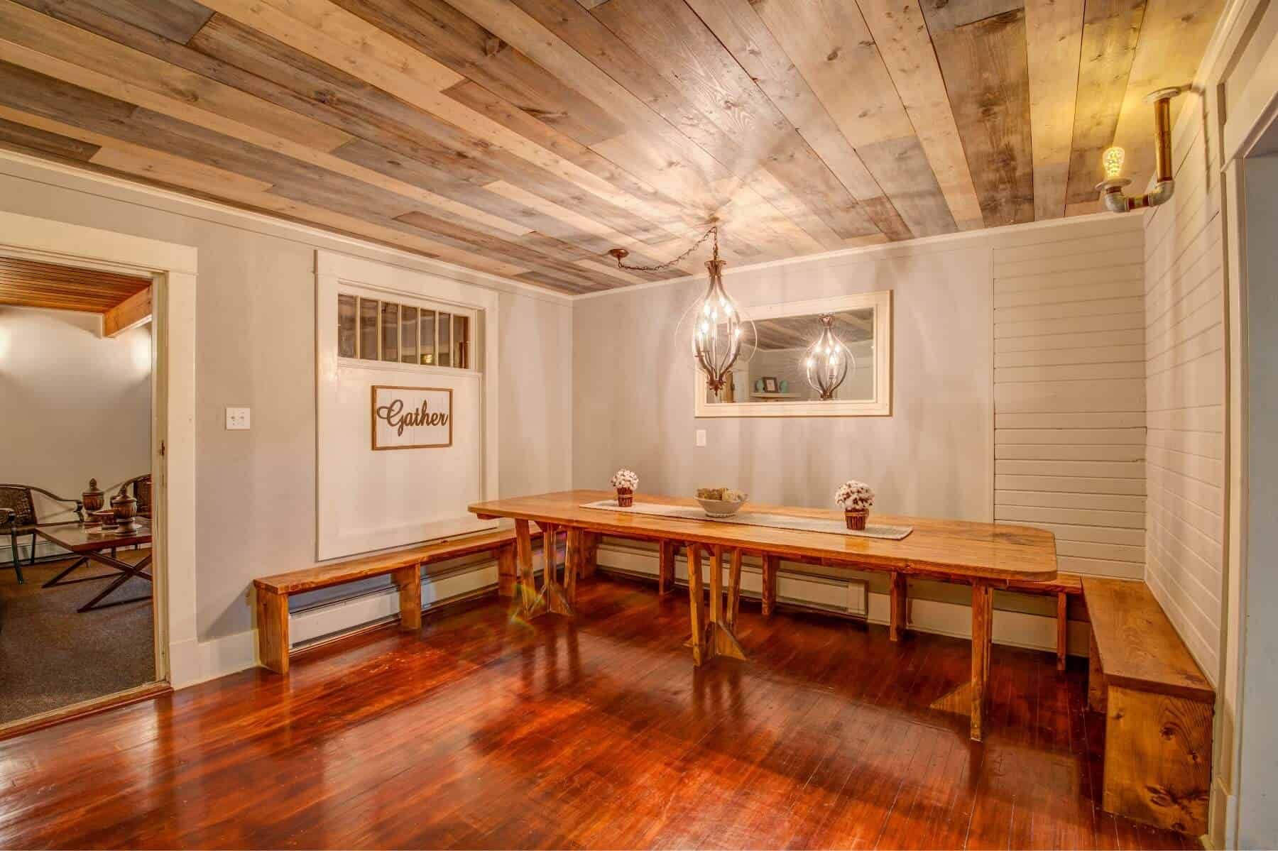 A spacious dining area with a wooden table, benches, and warm lighting from modern fixtures.