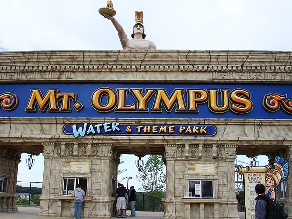 Entrance to Mt. Olympus Water & Theme Park, featuring a large statue and ticket booths.