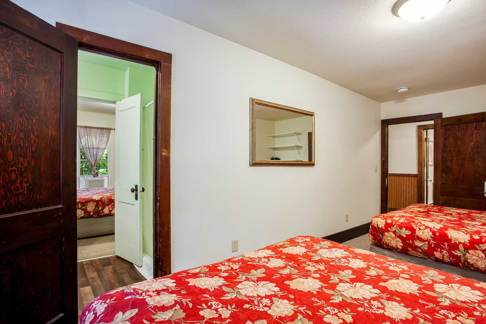 A cozy room with two beds featuring floral bedding and a doorway leading to another space.